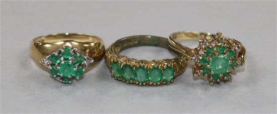 Two 9ct gold, emerald and diamond cluster dress rings and a 9ct gold and five stone emerald half hoop ring.